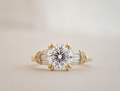 Front view of The Amelia Brilliant with a round brilliant-cut lab-grown center diamond and tapered baguette side stones in yellow gold.